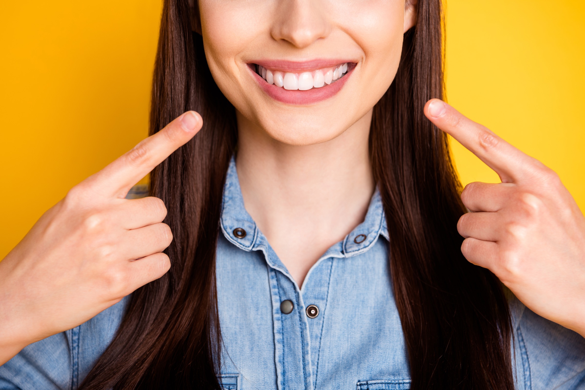 Close up photo of a girl pointing her index fingers to her teeth